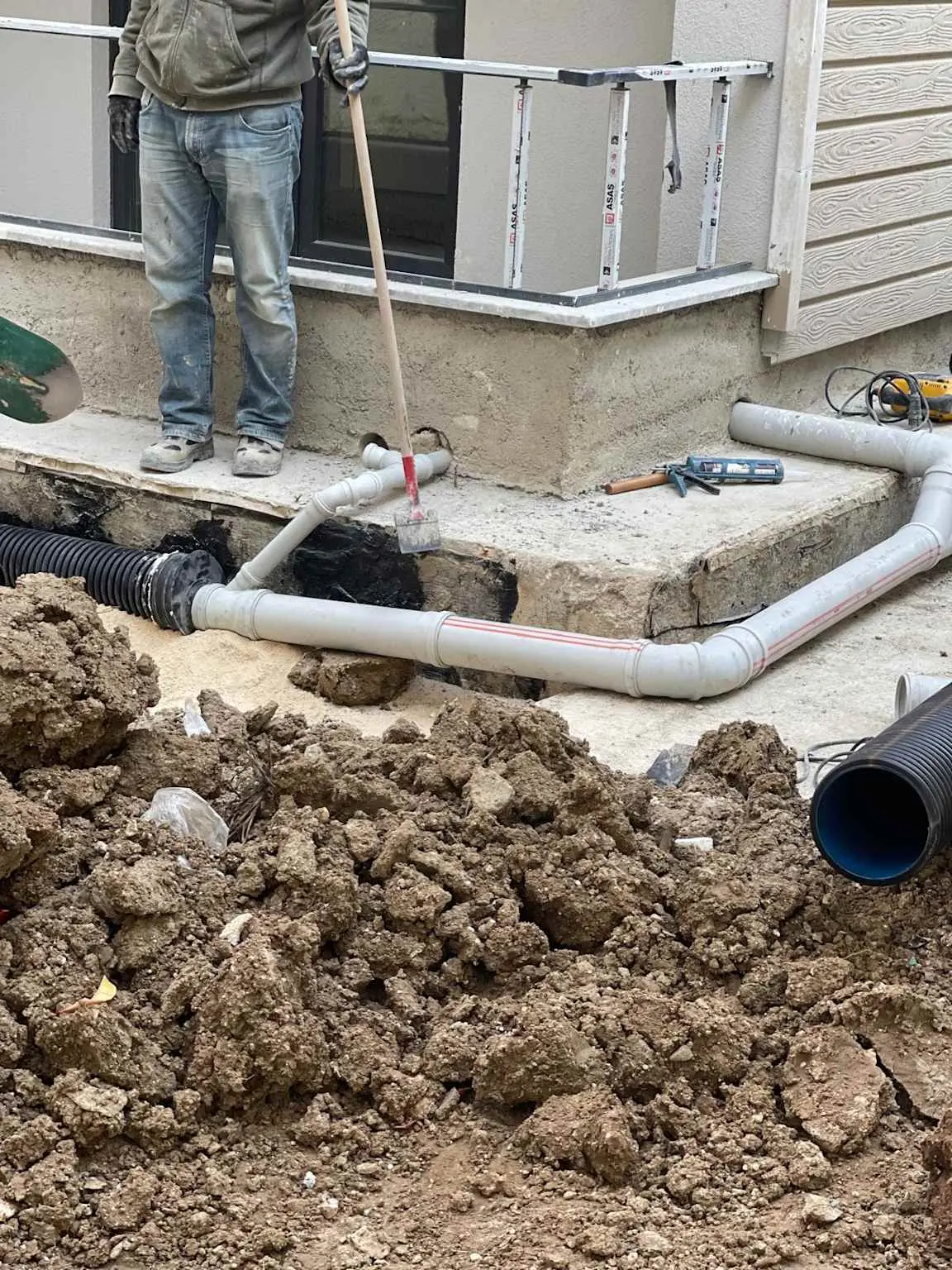 Bina önü şantiyede PVC yağmursuyu boru bağlantısı ve HDPE koruge boru döşeme; zemin kazısı, dirsek eki ve yapı bağlantı detayı