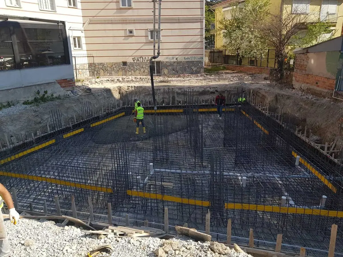 Büyük ölçekli radye temel donatı montajı — çift katlı ızgara donatı, kolon bekleme çubukları ve işçiler