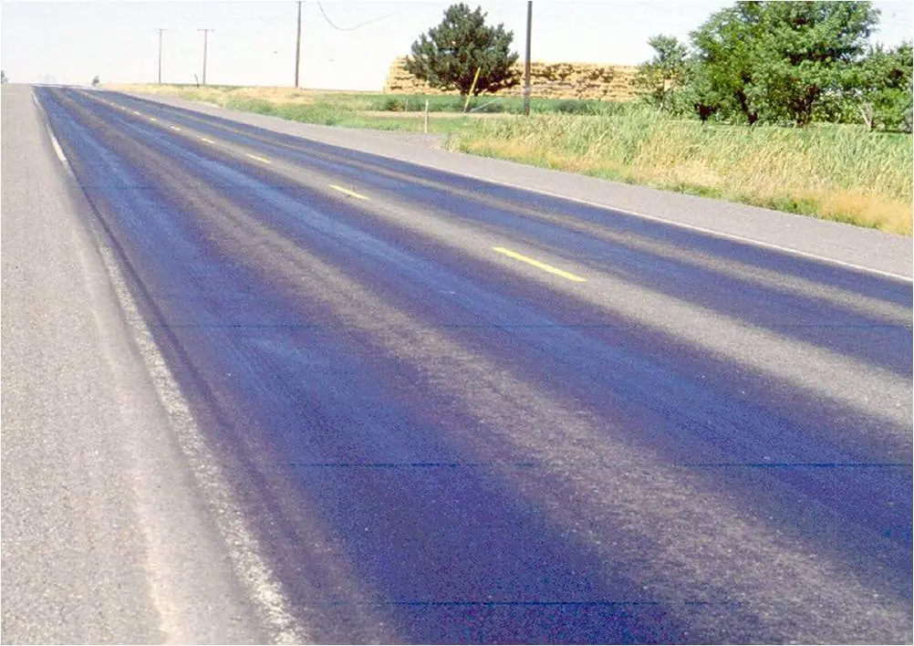 Kırsal devlet yolunda boyuna çatlak ve tekerlek izi bozulması — siyah asfalt yüzeyinde rutting ve cracking hasar tipleri