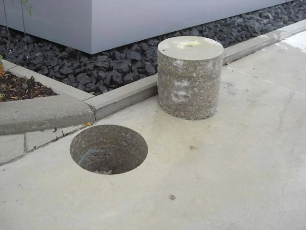 Beton döşemeden karot deliği ve yanına konulmuş çıkarılmış silindirik karot numunesi