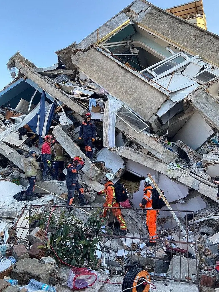 Deprem hasarı görmüş binada çökmüş kolon ve kiriş enkazı; arama kurtarma ekipleri enkaz üzerinde çalışmakta