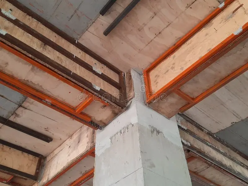 İnşaat sahasında kiriş-kolon köşe birleşimi: kalıp söküldükten sonra beton yüzeyi görünen kolon ve kirişler; turuncu renkli çelik kalıp çerçeveleri kiriş altında ve yanlarda görülmekte, köşe birleşim bölgesinde betonarme yapının geometrisi belirgin