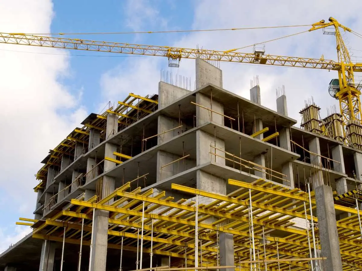 Sarı vinç ve beton perde duvarları olan yüksek bina inşaatı — transfer kirişi bulunan yapıda kalıp-iskele sistemi ve yoğun donatılı kat geçiş bölgesi görünümü