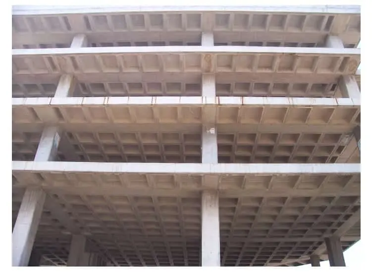 Çok katlı betonarme bina inşaatında döşeme-kolon sistemi dıştan görünüm: her katta tekrarlayan kaset döşeme kafes geometrisi, kolonlar arası bölmelerde eşit aralıklı kirişler ve 3 kat yüksekliğinde tamamlanmış çerçeve