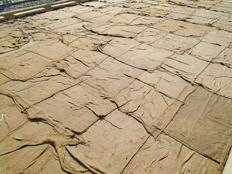 Islak jüt çuval (burlap) ile beton kürü uygulaması — beton yüzeyinde su kaybını önlemek amacıyla çuval serilmesi