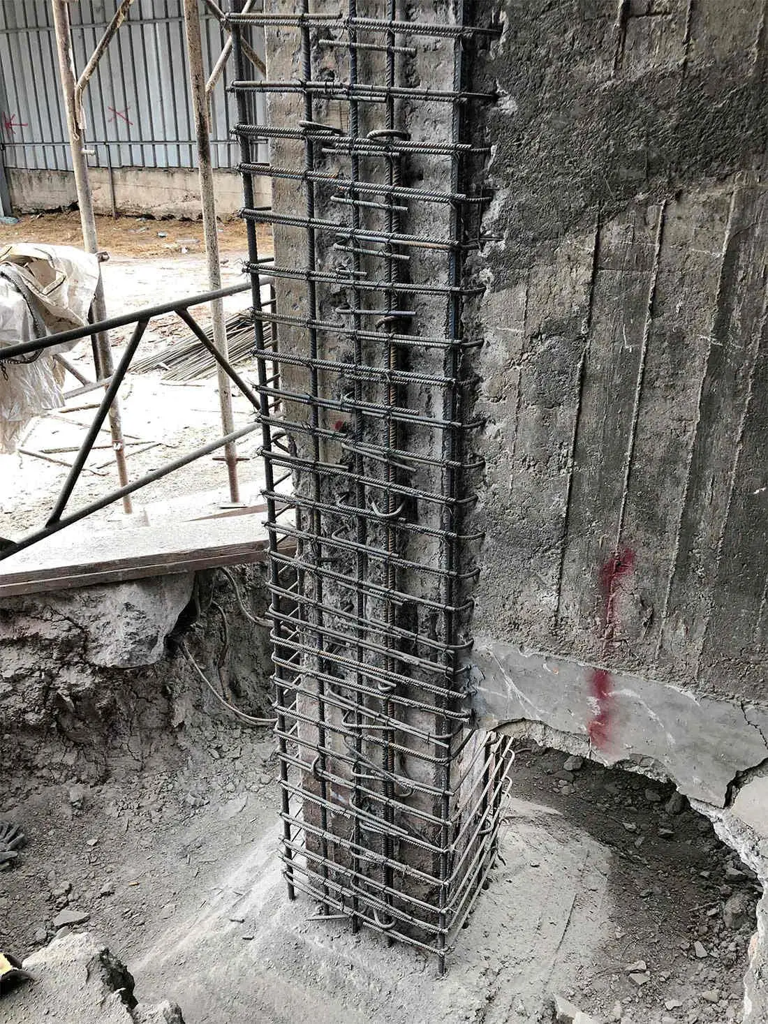 Betonarme mantosu uygulama sahası: kolon temel bölgesinde yeni donatı kafesi monte edilmiş, kimyasal ankraj çubukları mevcut betona sabitlenmiş
