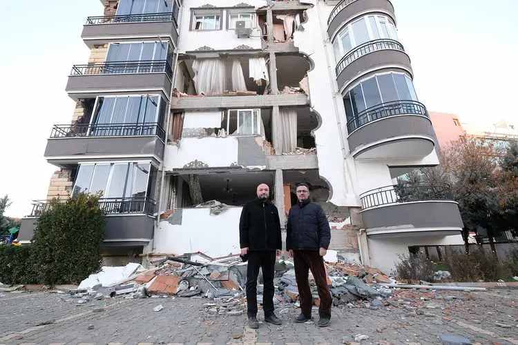 İnşaat şantiyesinde mühendis ve işçi — betonarme çerçeve ve perde imalatı devam eden yapı