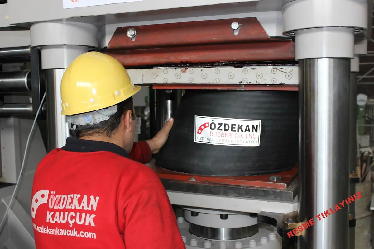 Özdekan Kauçuk izolatör test sahnesi: mühendis kauçuk izolatörü bir pres makinesinde incelerken