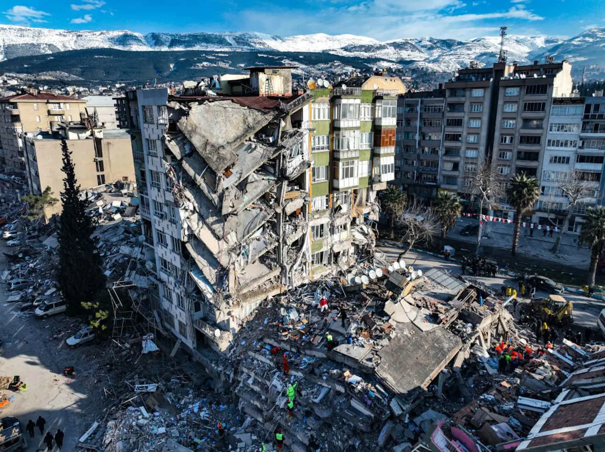 2023 Kahramanmaraş depremi sonrası yıkılan çok katlı betonarme bina — kat üste kat çökmesi ve yumuşak kat mekanizması görülüyor