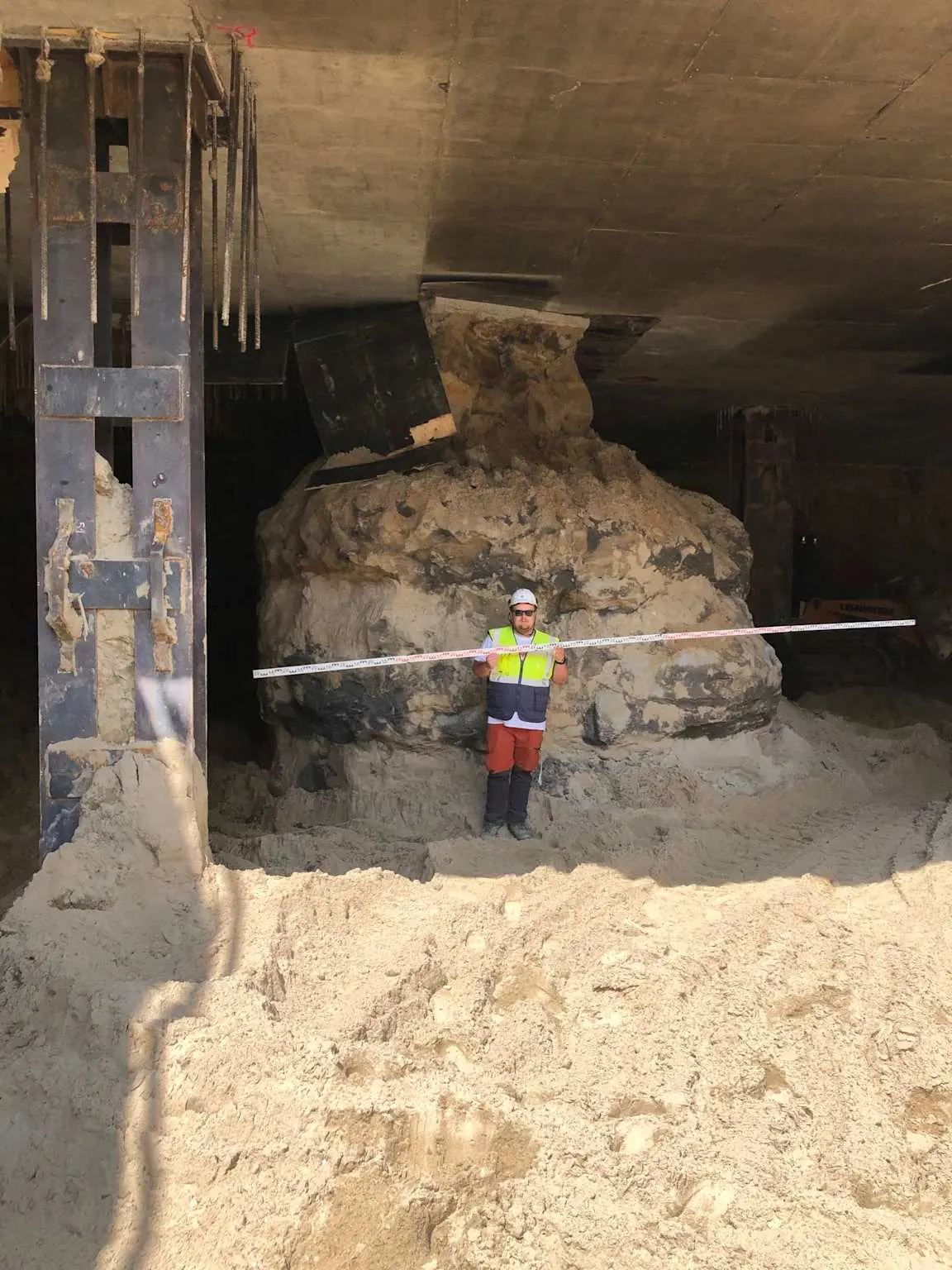Açık kazı içinde açığa çıkmış büyük jet grout kolonları; arka planda ahşap destek yapısı ve metal kasalar, önde işçi ölçek için durmakta, tahminen 1.5 metre çaplı kolon kümeleri görülmektedir