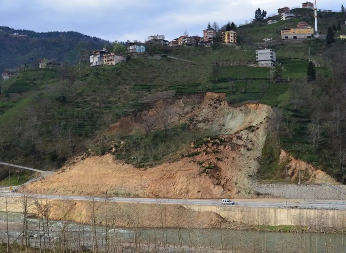 Doğu Karadeniz'de aktif heyelan: köy yerleşimi üstte, yol altta, ayrışmış tüf zeminde sığ dairesel kayma