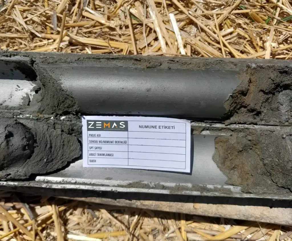 Türkiye'de SPT split-barrel numune: ZEMAS şirket etiketi, numune alıcı içi zemin örneği; sondaj no, derinlik, SPT sayısı ve arazi teknisyeni için boş etiket alanları görünüyor