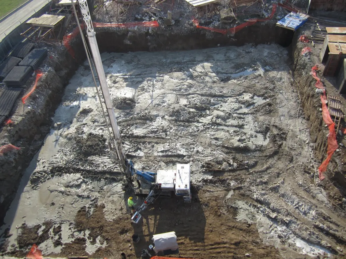 Jet grout kolonlar kazıyla ortaya çıkarılmış — beyaz-gri renkte soilcrete silindirik kolonlar kazı tabanında görünüyor, kırmızı güvenlik kordonları ile çevrili, üstten çekilmiş fotoğraf