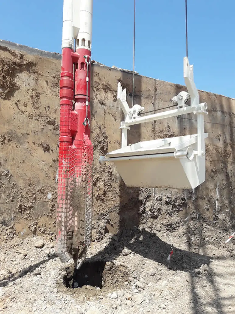 Türkiye'de kentsel bir kazı şantiyesinde kırmızı renkli Continuous Flight Auger (CFA) fore kazık makinesi ve beyaz renkli fore kazık kılıfı yerleştirme ekipmanı