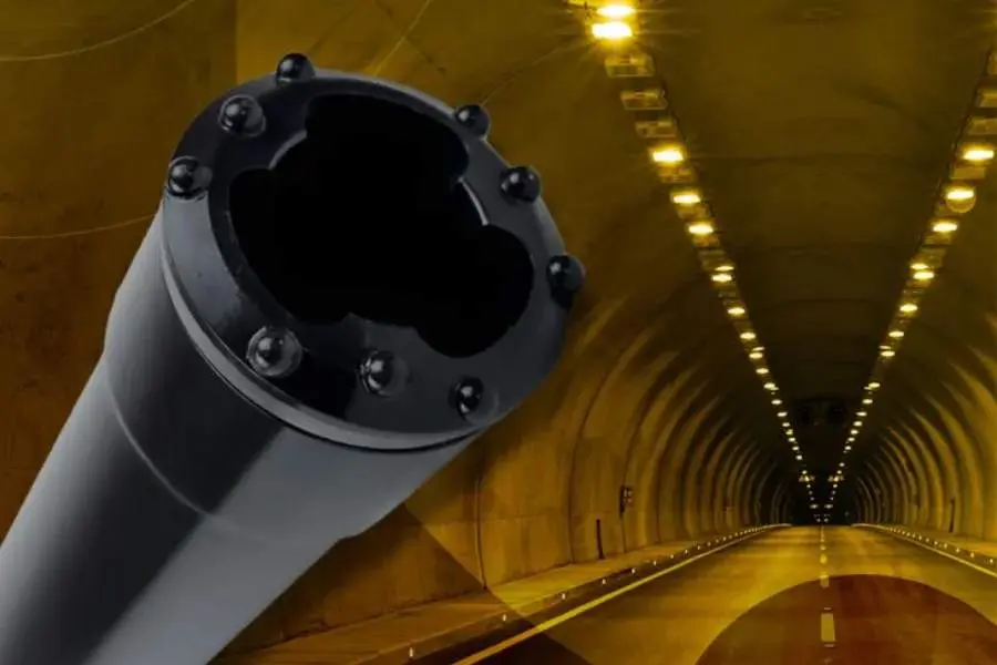 Şemsiye enjeksiyonu borusu (pipe roof) yakın çekim — çelik boru uç bağlantısı ve arka planda aydınlatılmış tünel iç koridoru