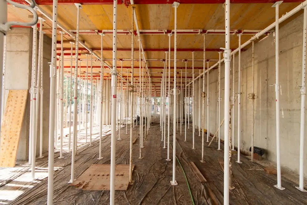 Döşeme kalıp destek sistemi — beyaz ayarlanabilir çelik dikmeler plywood yüzeyi taşıyor