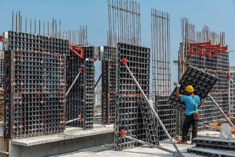 Modüler çelik panel kalıp sistemi montajı — işçiler büyük formwork panellerini birleştiriyor
