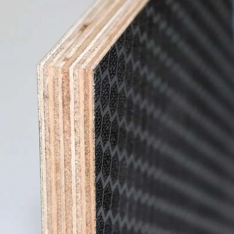 Kesilmiş çok katmanlı kontrplak kesiti yakın plan; sol kenarda birbiri üzerine yapıştırılmış ahşap katmanlar (birch veneer), sağ yüzeyde siyah ızgara desenli fenolik film kaplama görülmekte
