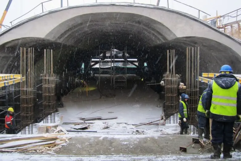 Karlı havada tünel altı şantiyesi — beton kolon donatı çubuklarıyla çevrilmiş büyük beton kemer