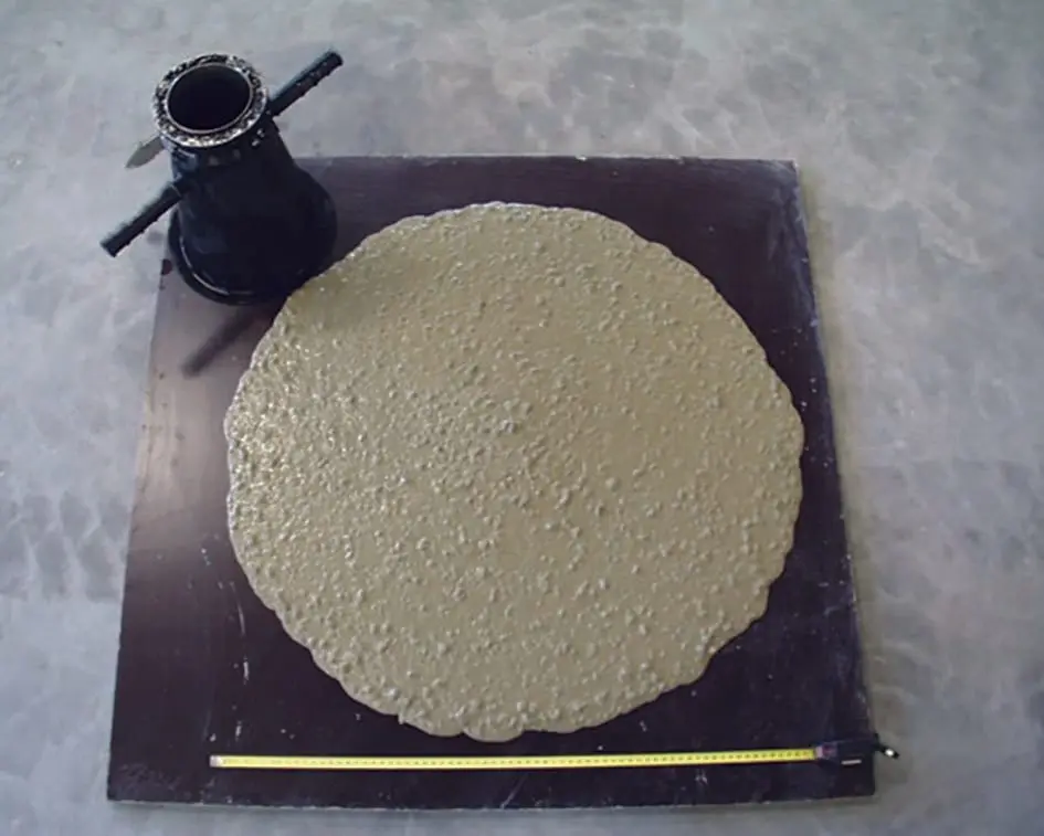 Akma tablası (flow table) testi — büyük daire şeklinde yayılmış taze beton ve ölçüm metre takozuyla