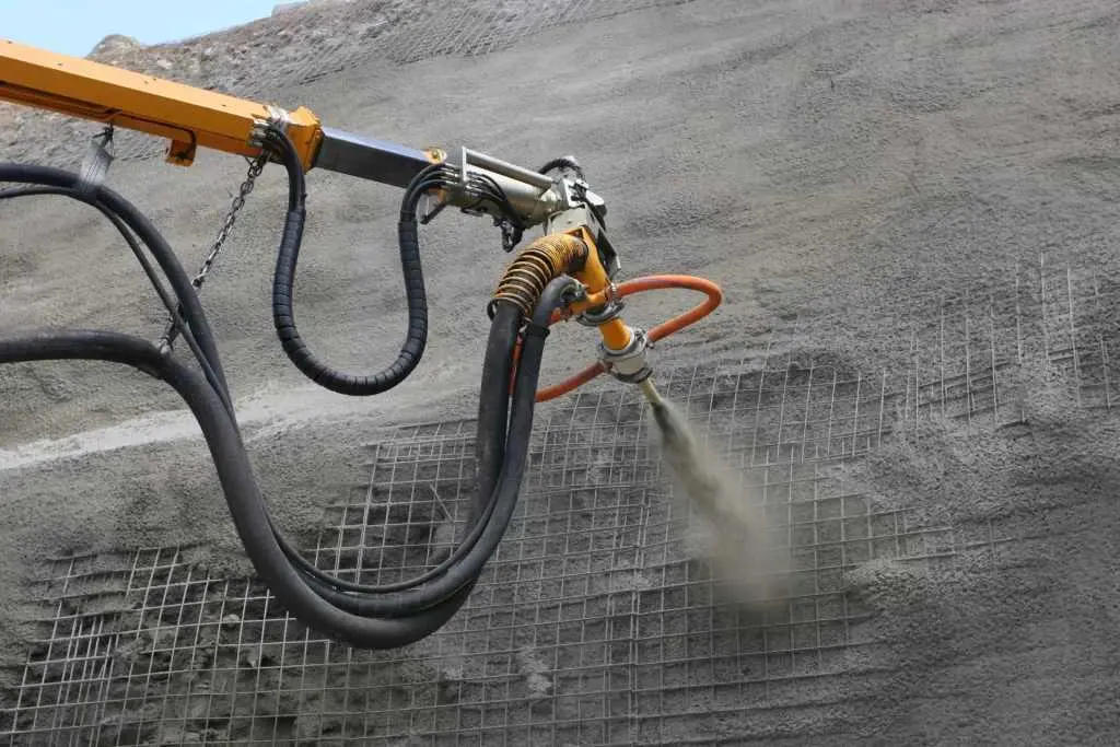 Robot kollu shotcrete ekipmanıyla tünel duvarına çelik lifli beton püskürtme (wet-mix shotcrete) uygulaması