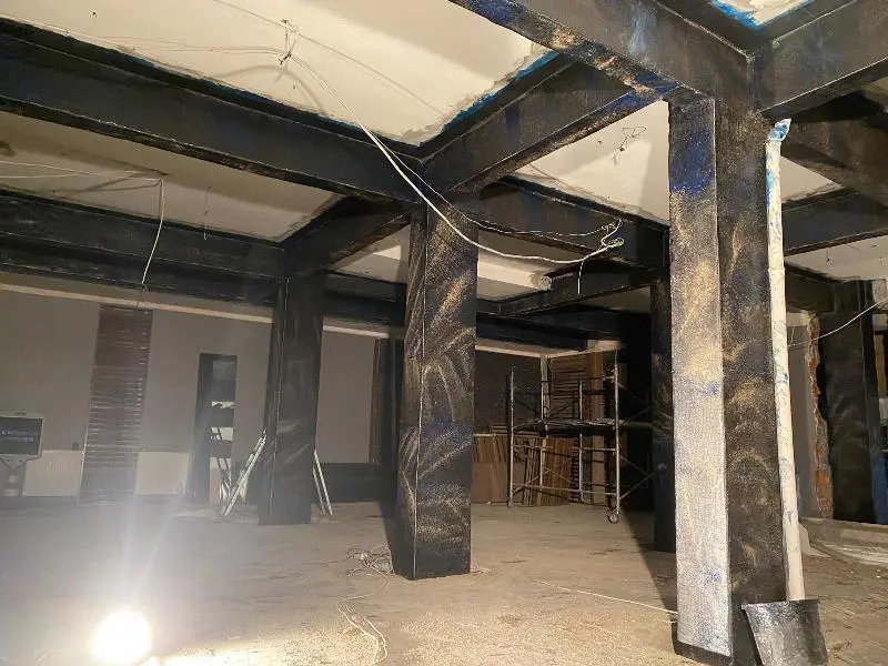 İç mekan betonarme kolon ve kirişler CFRP ıslak sargı ile güçlendirilmiş — siyah sarılı yapı elemanları