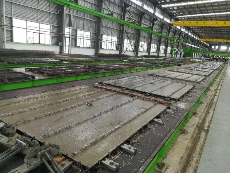 Büyük bir prefabrik beton üretim tesisinde paralel yataklama tablası hatları — stressing bed üzerinde tendonlar serilmiş ve beton dökümüne hazır