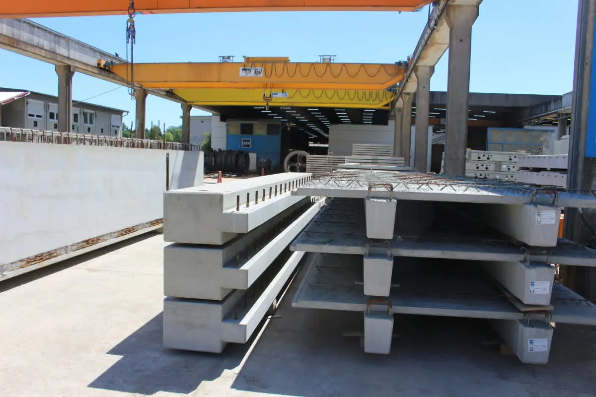 Prefabrik öngerilmeli kirişlerin üretim sonrası açık alanda istiflenmesi — yan yana sıralanmış I-kirişleri, beton yüzeyi görünür