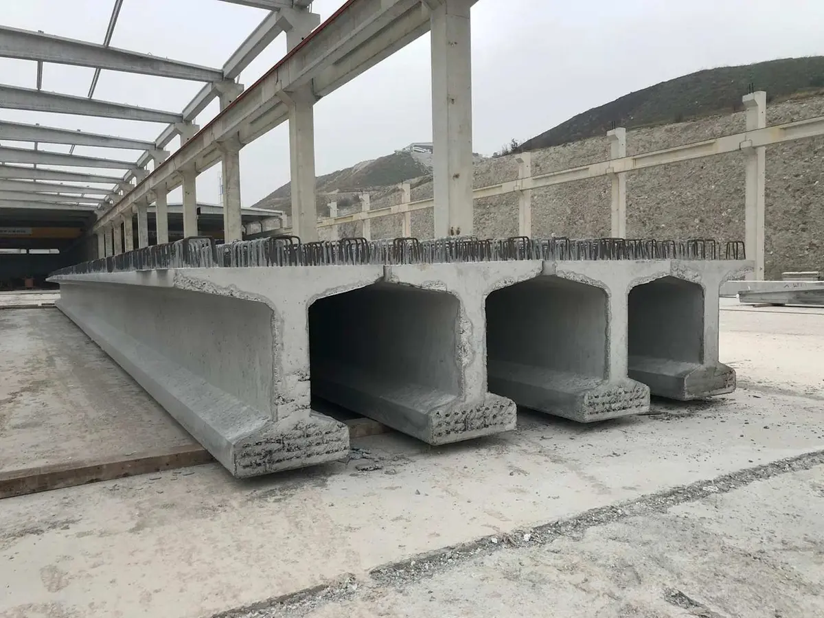 Türkiye'de prefabrik öngerilmeli köprü kirişleri fabrika depolarında: U-kesitli kirişlerin alt flansından strand uçları görünür