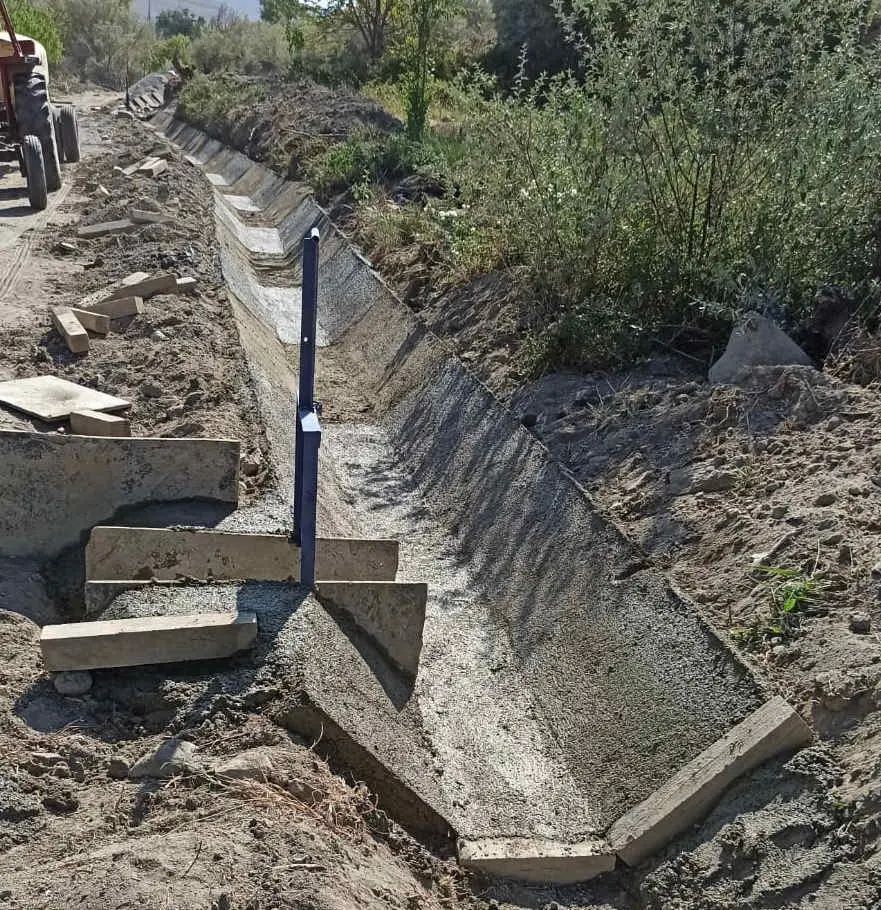 Trapez kanal kesit parametreleri şeması — su yüzeyi genişliği w, derinlik h, taban genişliği b, yan eğimler z1 ve z2, mavi taramalı ıslak alan