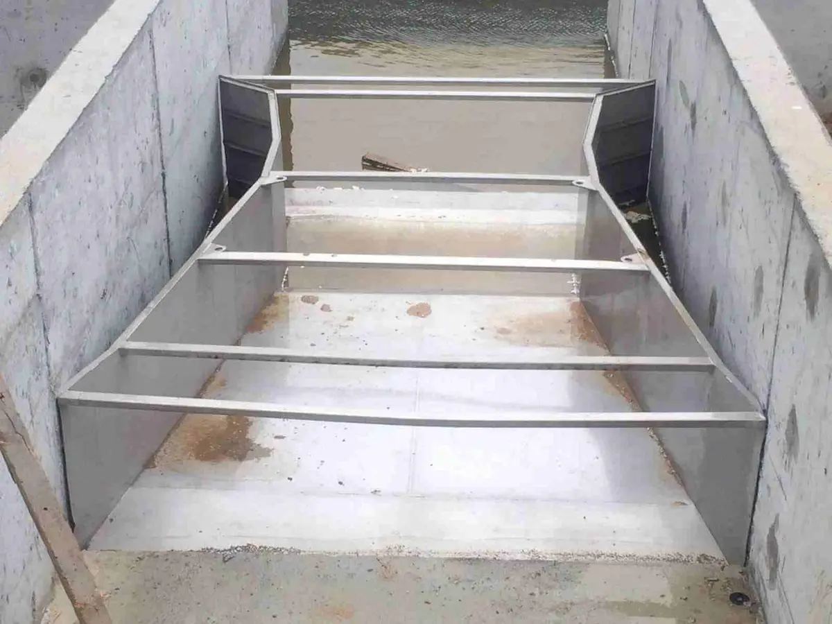 Metal levhadan yapılmış çok dilli dikdörtgen savak plakası kanal içinde kurulu — paslanmaz çelik, beton kanal tabanına montajlı
