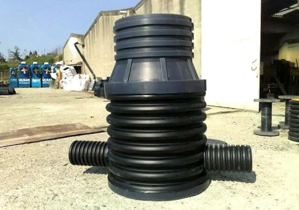Siyah HDPE prefabrik muayene bacası bileşenleri saha fotoğrafı — gövde, konik üst ve iki boru bağlantısı