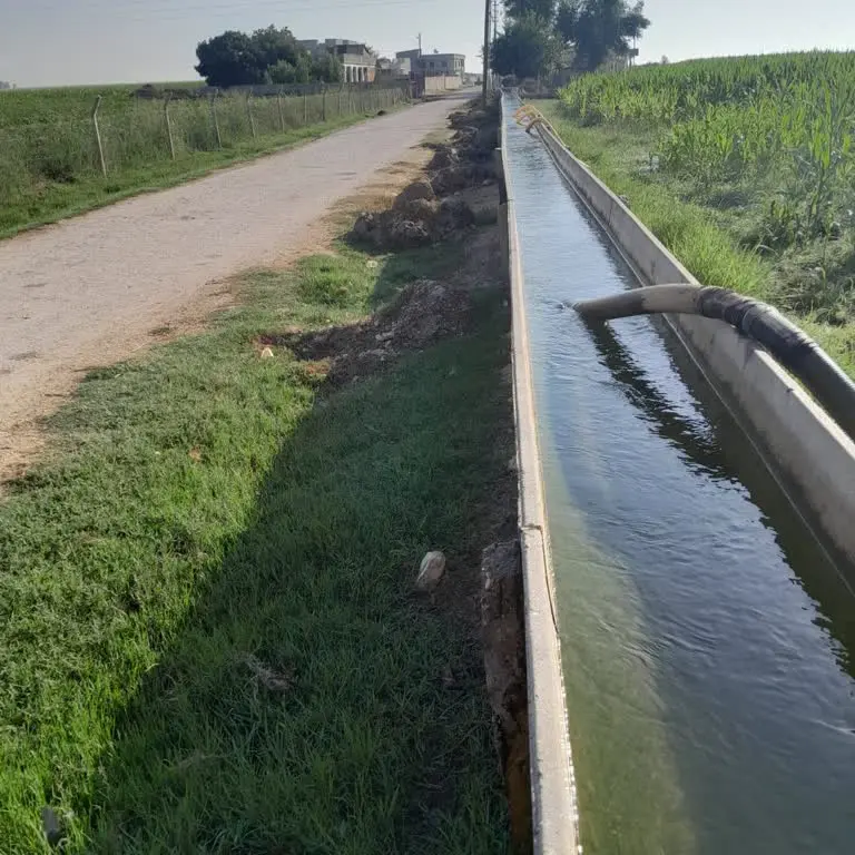 Su akan trapez beton sulama kanalı tarla kenarı saha fotoğrafı — yol boyunca uzanan sızdırmaz beton kanal