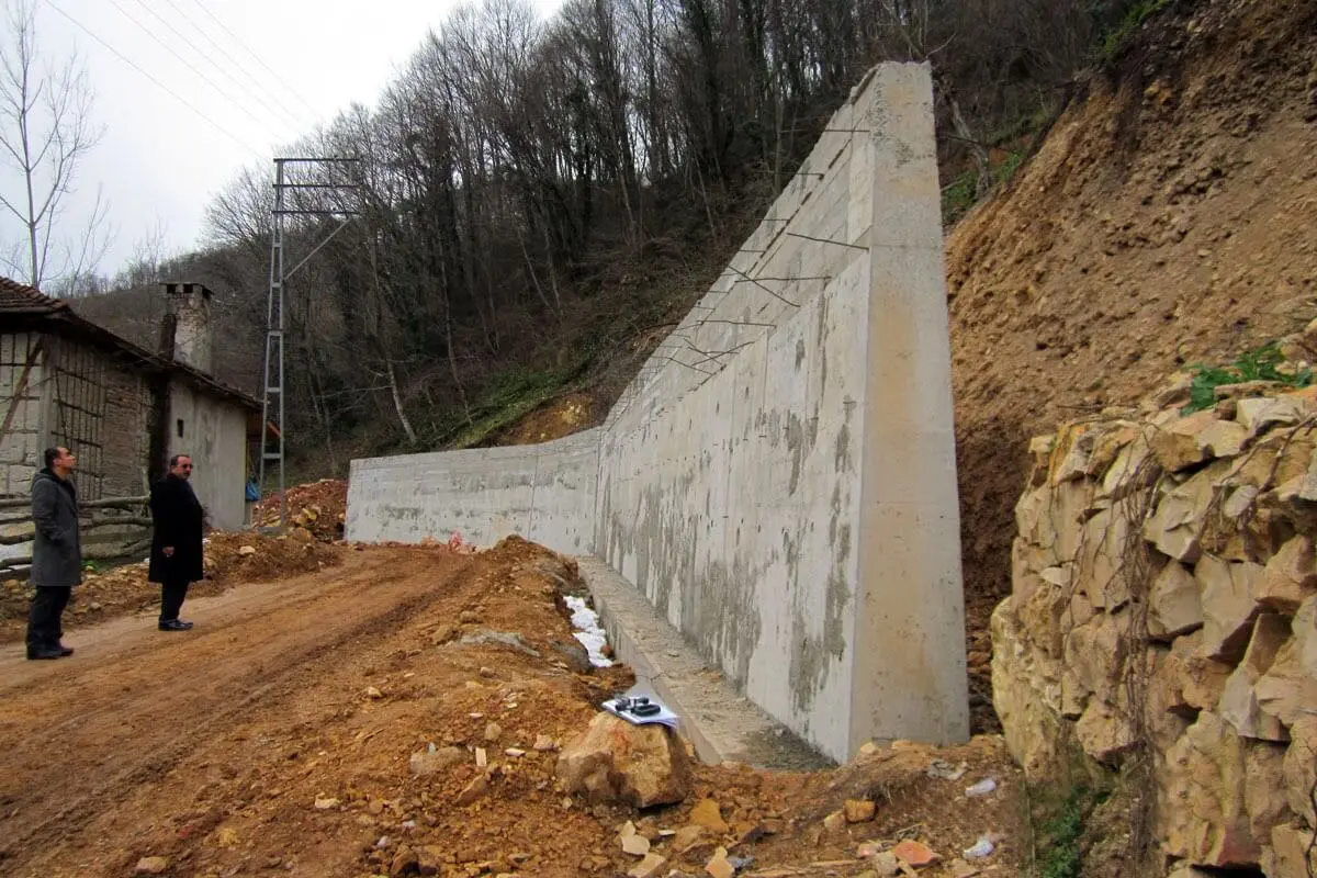 Türkiye şantiyesinde sahada inşaat halindeki beton istinat duvarı: kırma taş drenaj dolgulu, barbakan delikli, eğimli dağ kenarı
