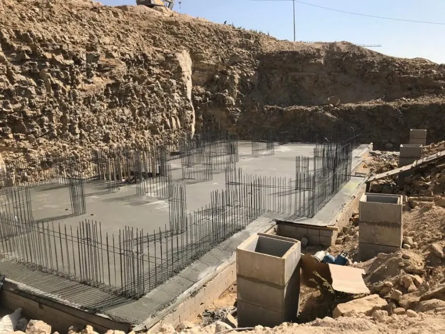 Radye temel inşaatı — beton dökülmüş, kolon donatıları çıkıntılı, kazı çukuru