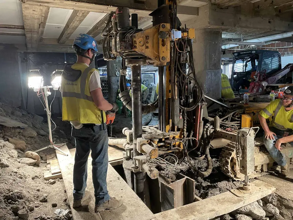 Dar kapalı alanda mevcut bina altında mikro kazık uygulaması — bodrum katta temel güçlendirme (underpinning) için küçük delgi ekipmanı, ışık ve grout enjeksiyon hortumları