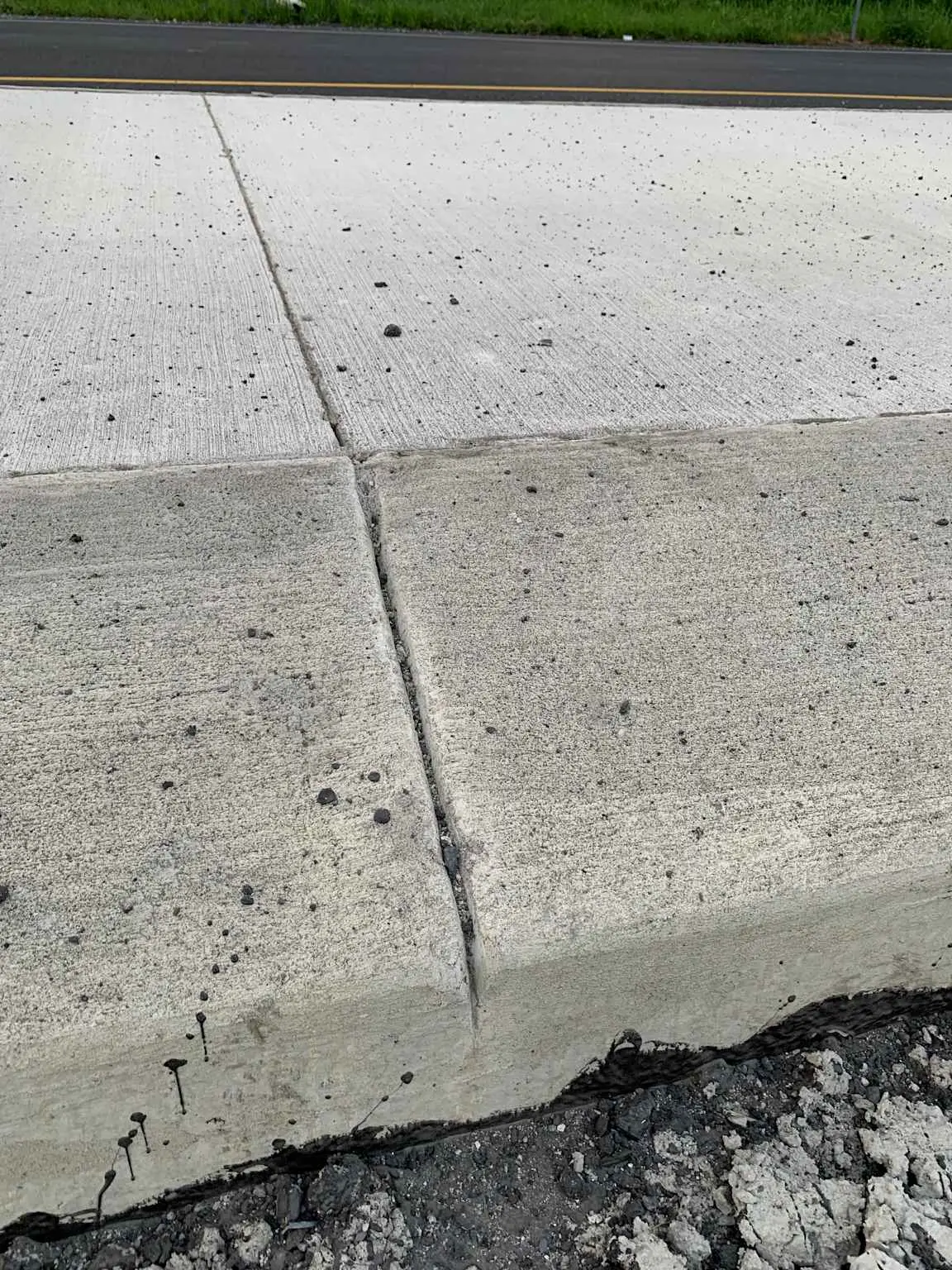 Beton yol yüzeyine yakın çekimde enine büzülme derzini gösteren fotoğraf; derz çizgisi plak yüzeyinde belirgin olarak görünüyor, plakların renk ve doku farkı seçilebiliyor