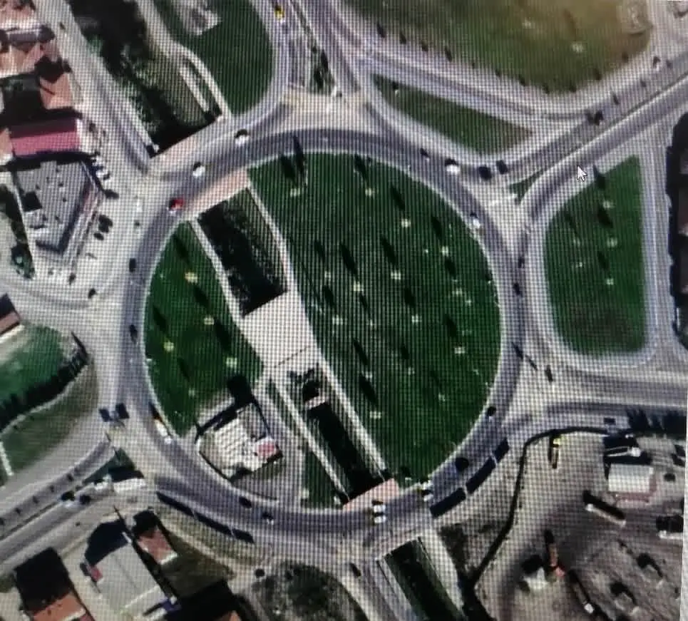 Türkiye'de dört kollu büyük bir dönel kavşağın hava fotoğrafı; geniş yeşil merkez adası ve çevresindeki gri dairesel yol, dört kolda yaklaşım yolları ve bölücü adalar görülüyor