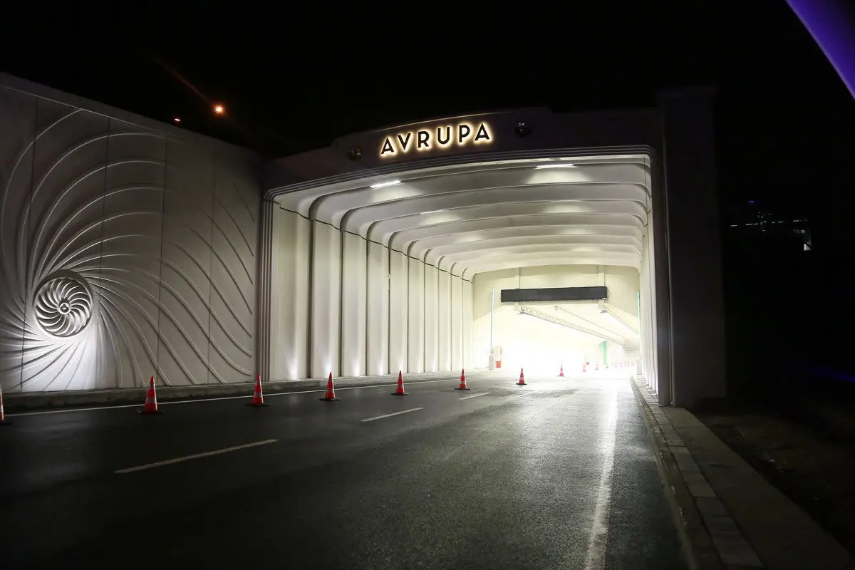 Gece çekimi Avrasya Tüneli Avrupa tarafı portali; portal duvarında spiral kabartma dekorasyon, üstte AVRUPA yazılı LED tabela, tünel içinde trafik konileri ve yüksek tavanın beyaz LED aydınlatması